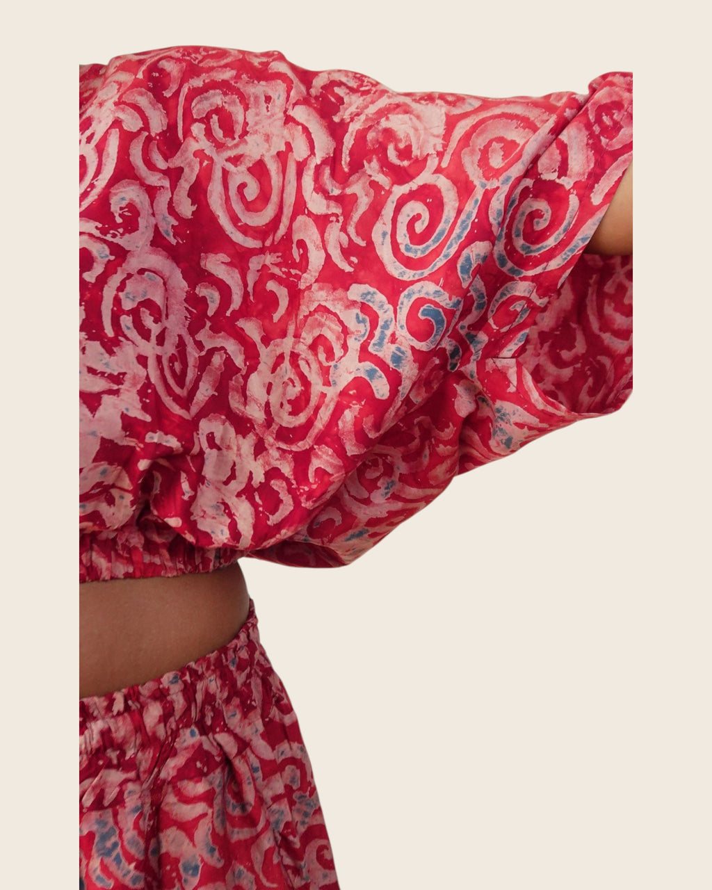 Simi Garnet Swirl — hand-dyed Adire fabric detail, blush swirls with slate-blue touches on garnet red, close-up of the batwing sleeve, L'atelier KaAy