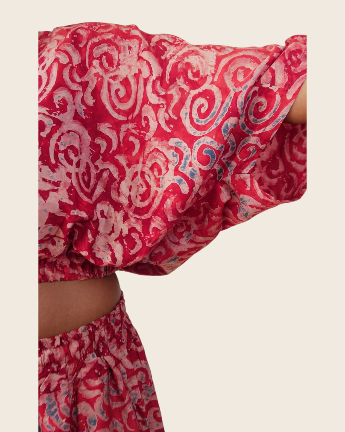 Simi Garnet Swirl — hand-dyed Adire fabric detail, blush swirls with slate-blue touches on garnet red, close-up of the batwing sleeve, L'atelier KaAy