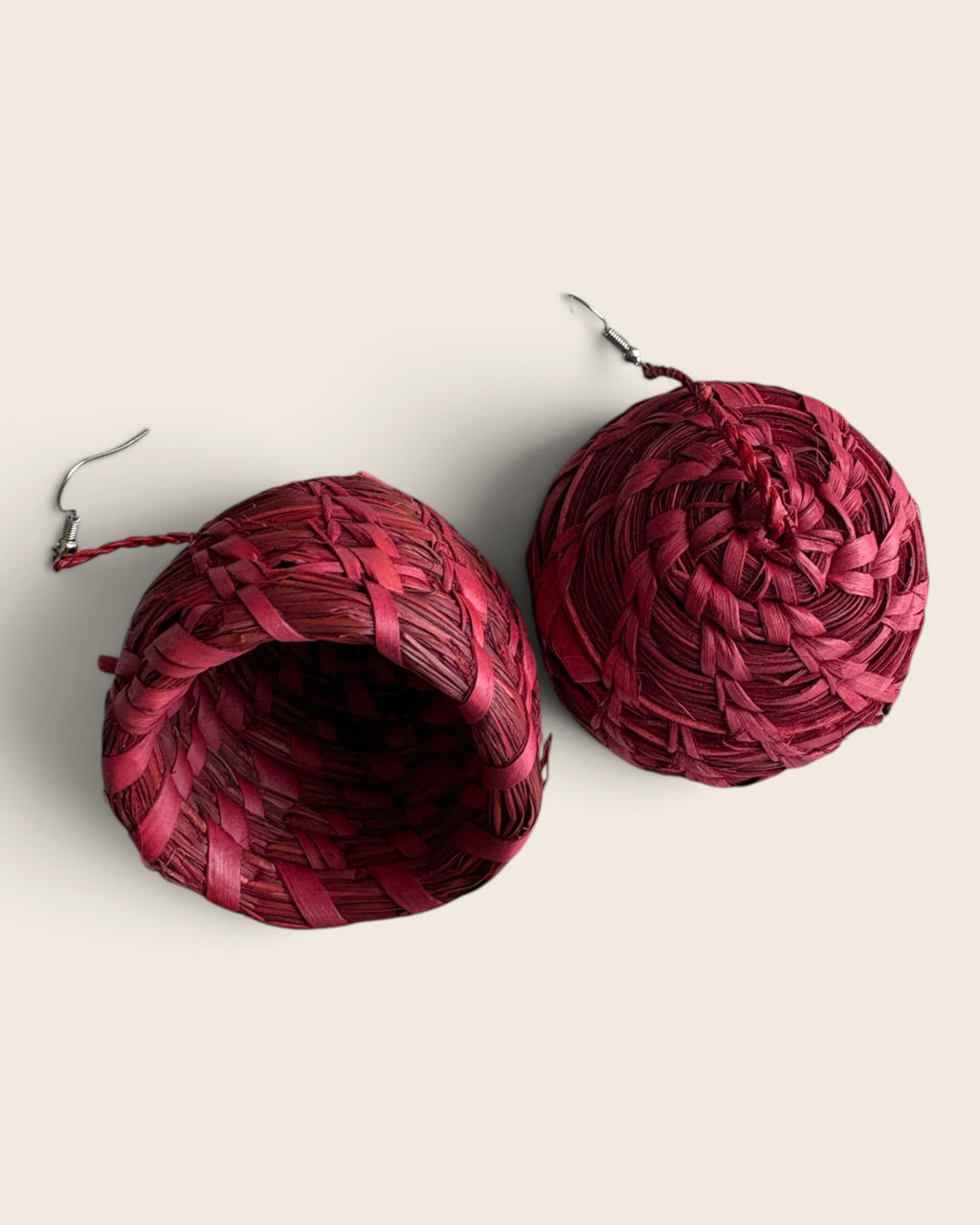 Cinnabar Red hand-woven raffia bell earrings showing the hollow bell and stainless steel ear wires, L'atelier KaAy