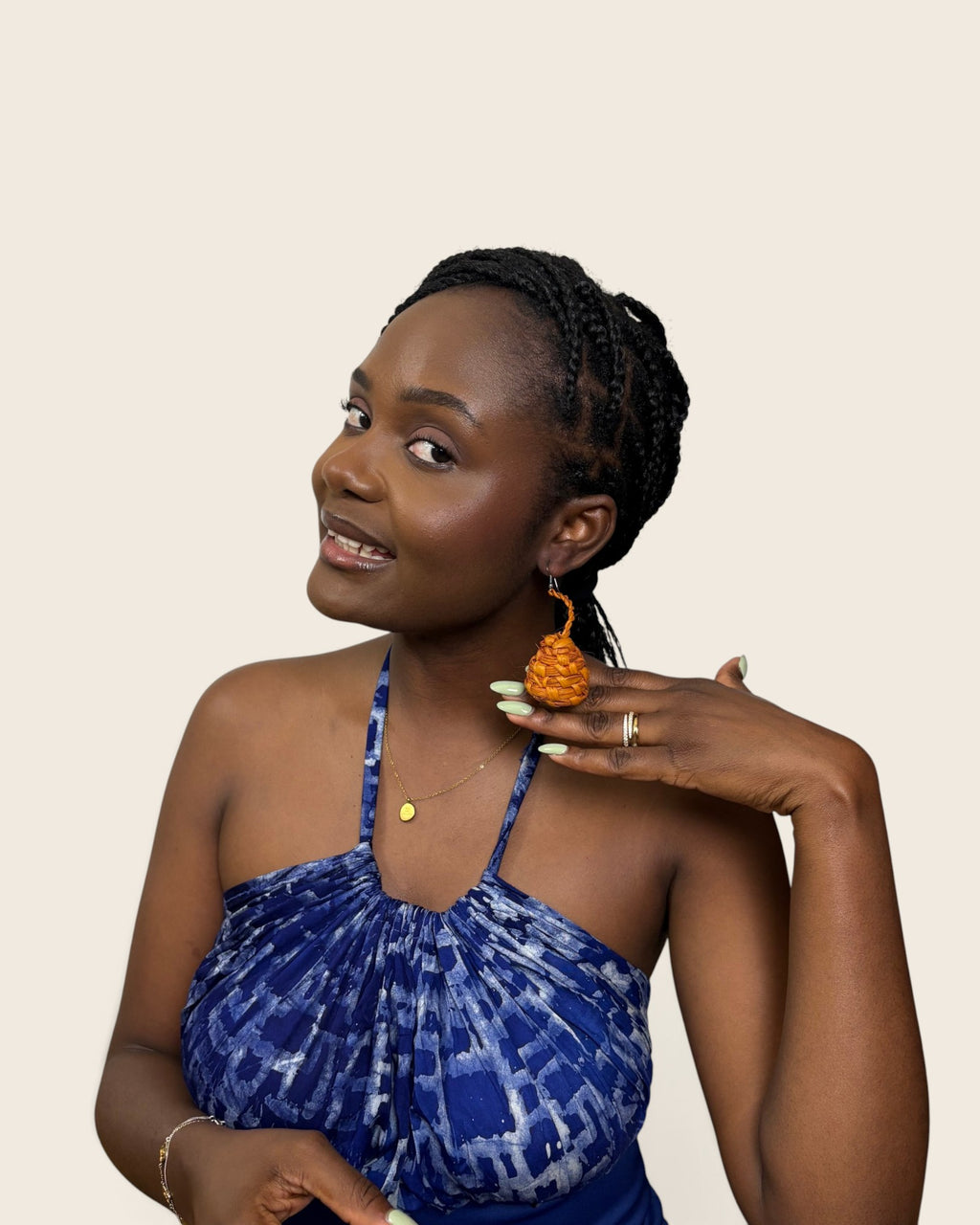 Close-up of handmade Nigerian raffia coiled teardrop earrings in a warm amber tone.