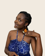 Close-up of handmade Nigerian raffia coiled teardrop earrings in a warm amber tone.