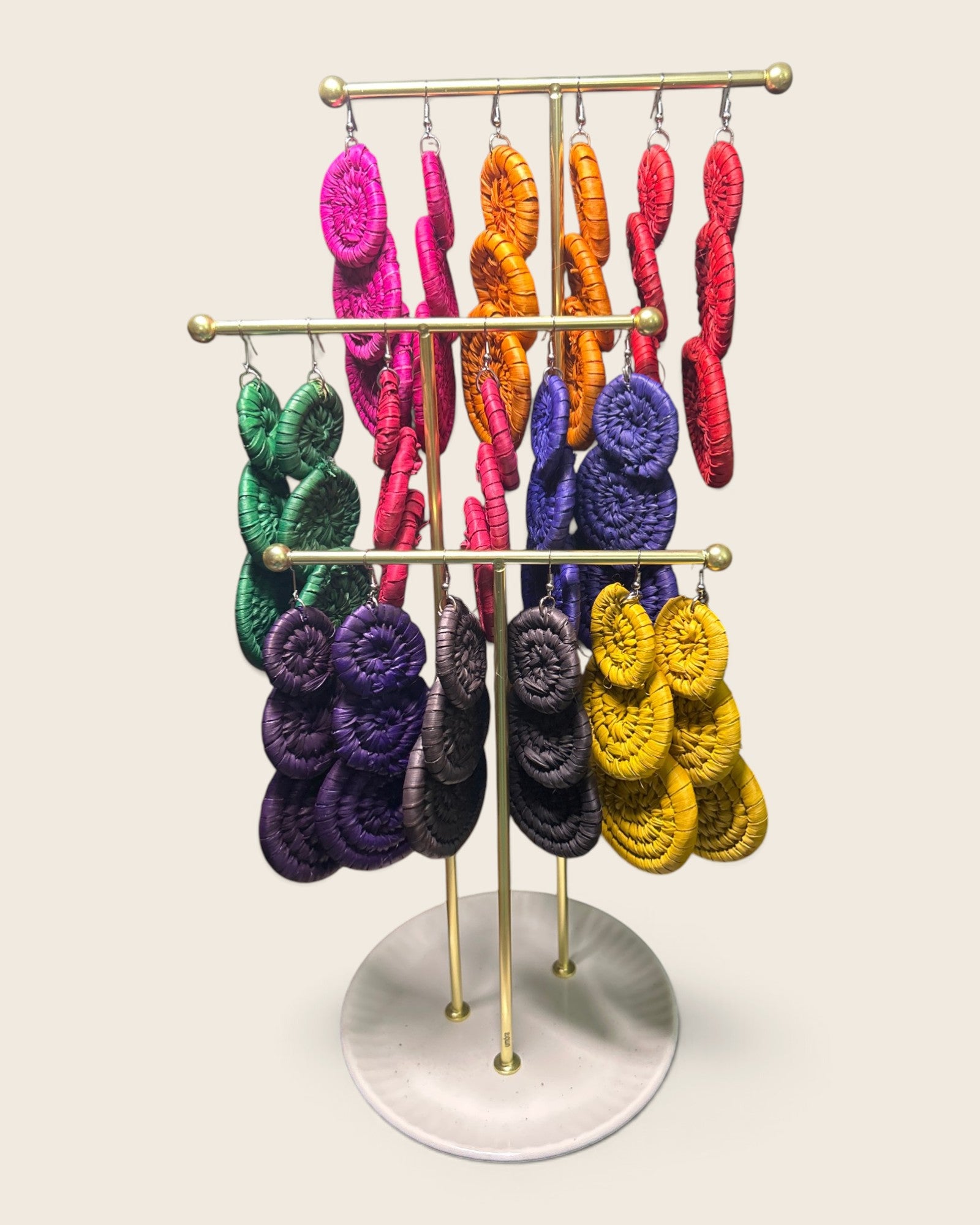 Zola triple disc raffia earrings in all nine hand-dyed colourways on a brass stand, hand-woven in Nigeria